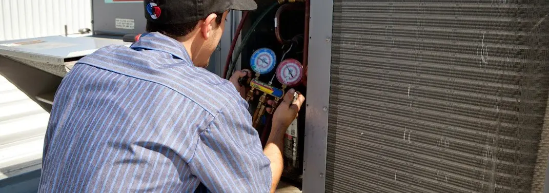 HVAC technician servicing a condenser unit in East Huntingdon