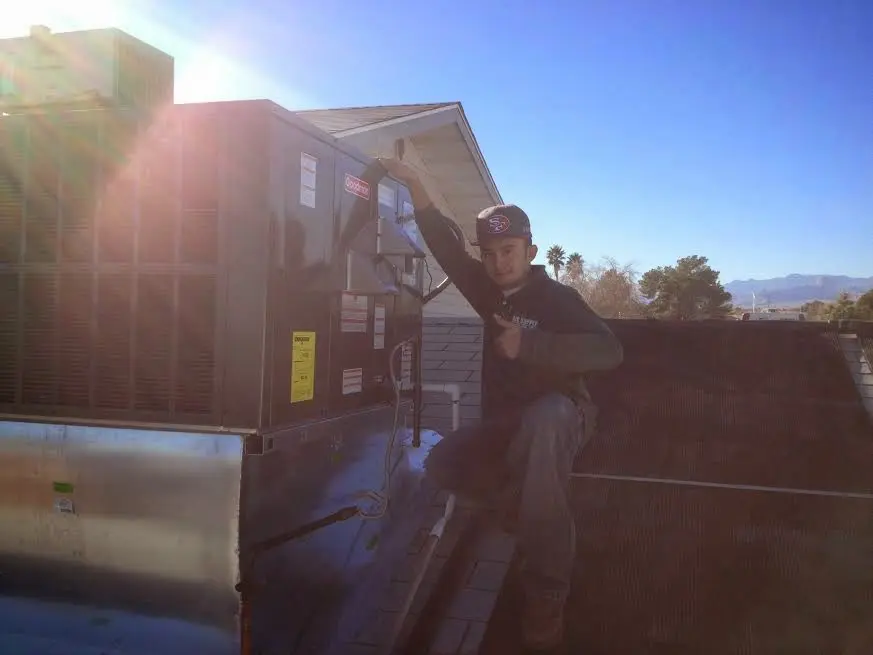 HVAC technician performing Air Duct Cleaning on a rooftop unit in East Huntingdon